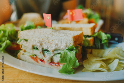 A club sandwich on a rustic table in bright lighte 