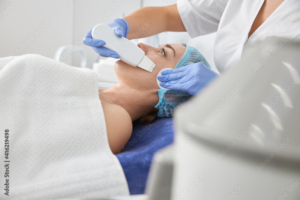 Professional cosmetologist is doing procedures for client in light cabinet Professional cosmetologist is doing procedures for client in light cabinet