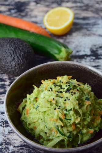 Fresh Tasty Vegetable Vegetarian or Vegan Grated Salad with Carrot Zucchini Sesame and Avocado Sauce in A Bowl