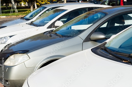 White and gray cars stand in a row in the parking lot