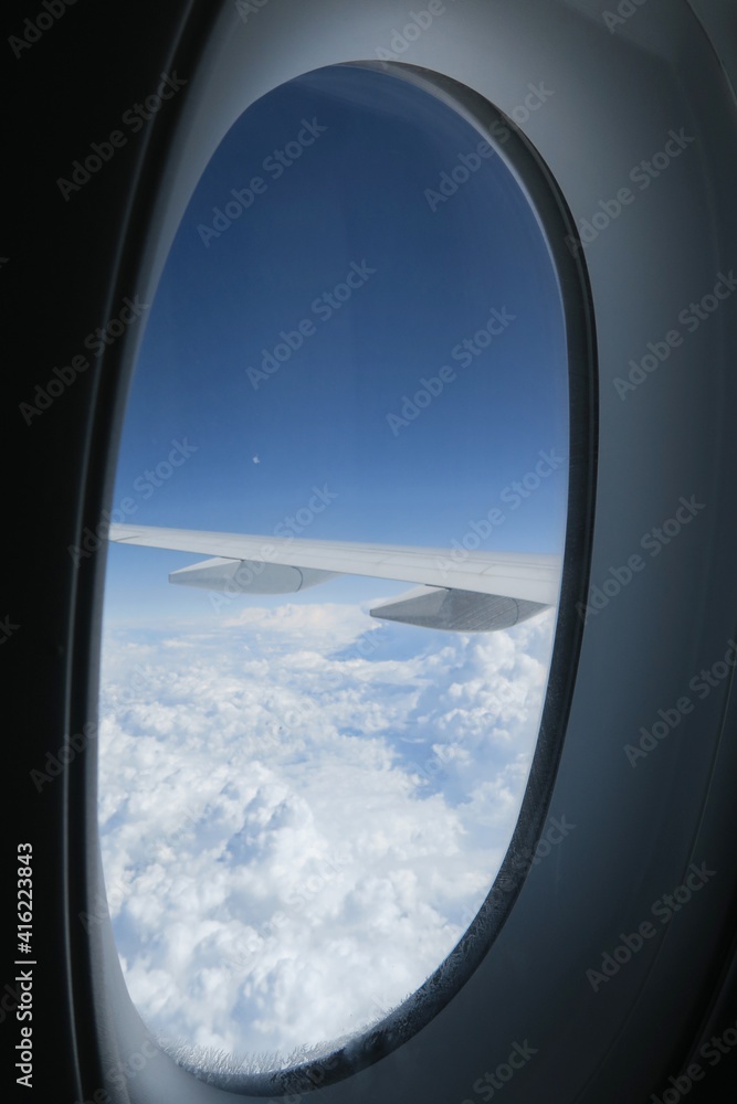 View from an airplane window with blue sky and clouds.