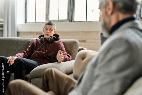 Tableau sur toile Upset teenage boy talking to professional psychotherapist