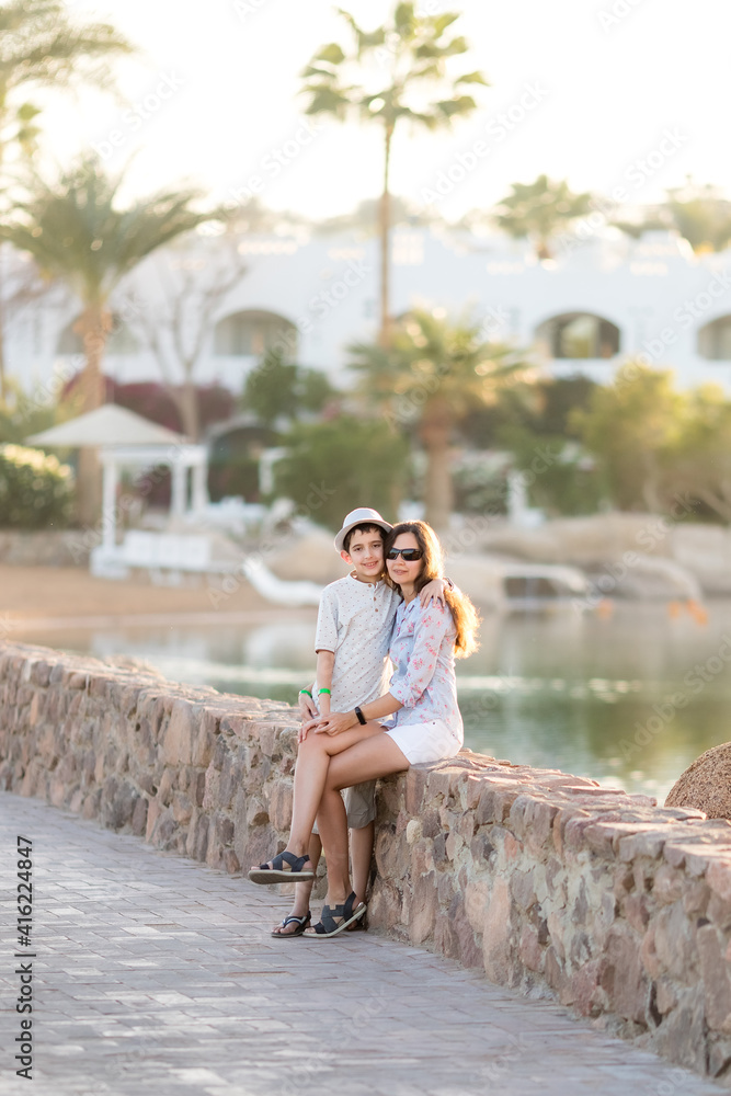 
Boy in the t-shirt and woman in white shorts and blouse on summer landscape. Mother and son. Family holidays. Vacation
