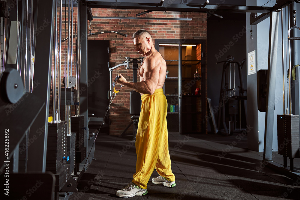 Naklejka premium Muscled man in comfortable sportsgear working out at gym