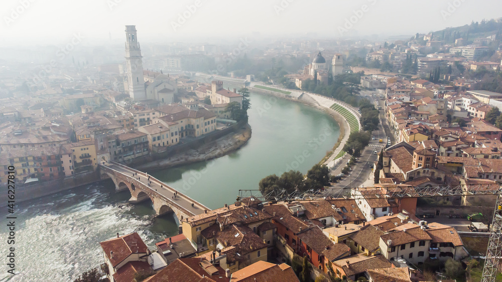 Aerial view of Verona crossed by the Adige river and shrouded in winter fog.