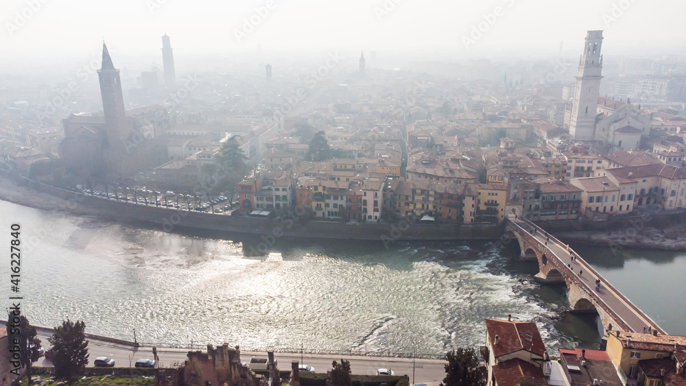 Aerial view of Verona crossed by the Adige river and shrouded in winter fog.
