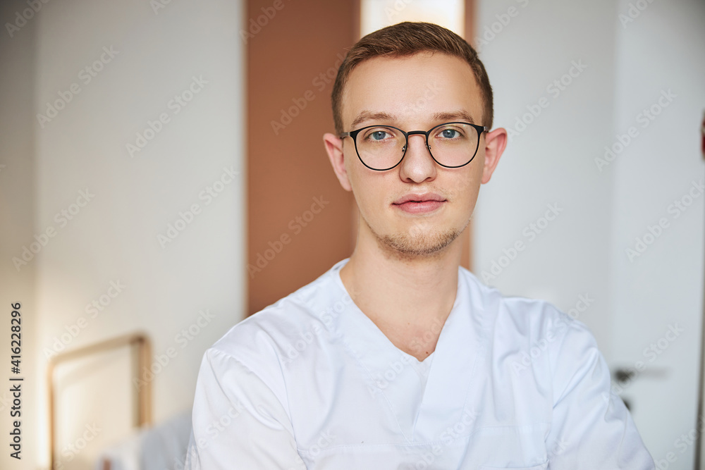 Bespectacled tranquil doctor waiting for his patients Bespectacled tranquil doctor waiting for his patients