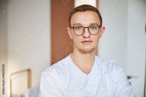 Bespectacled tranquil doctor waiting for his patients