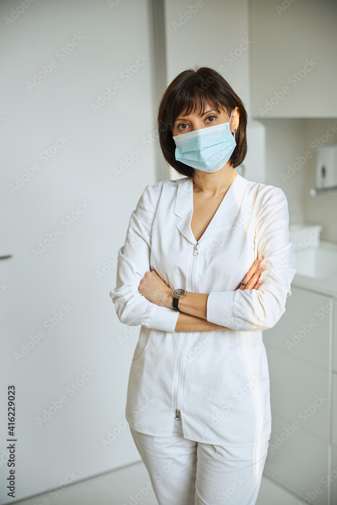 Serious physician wearing a face mask at work Serious physician wearing a face mask at work