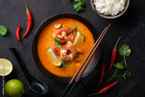 Foto Tom Yum kung Spicy Thai soup with shrimp in a black bowl on a dark background, t
