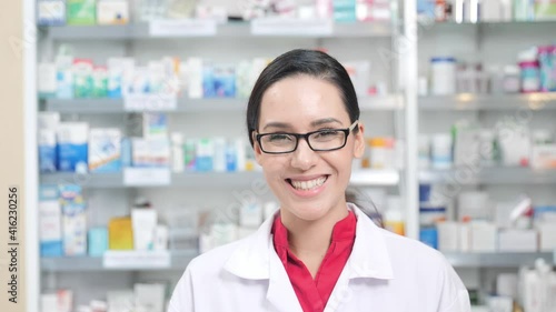 women pharmacist smiling confident and looking at the camera in modern pharmacy. Slow motion photo