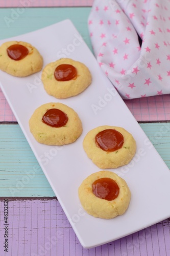 Homemade thumbprint cookies with jam on white serving plate. pastel color background 