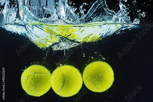 Tennis ball falling in water with a splash against dark background photo