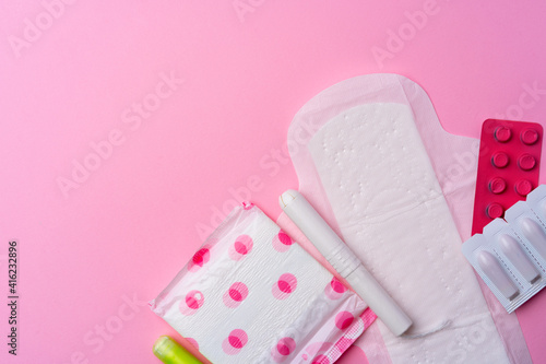 Сontraceptive pills, hygienic pads and tampons on pink background