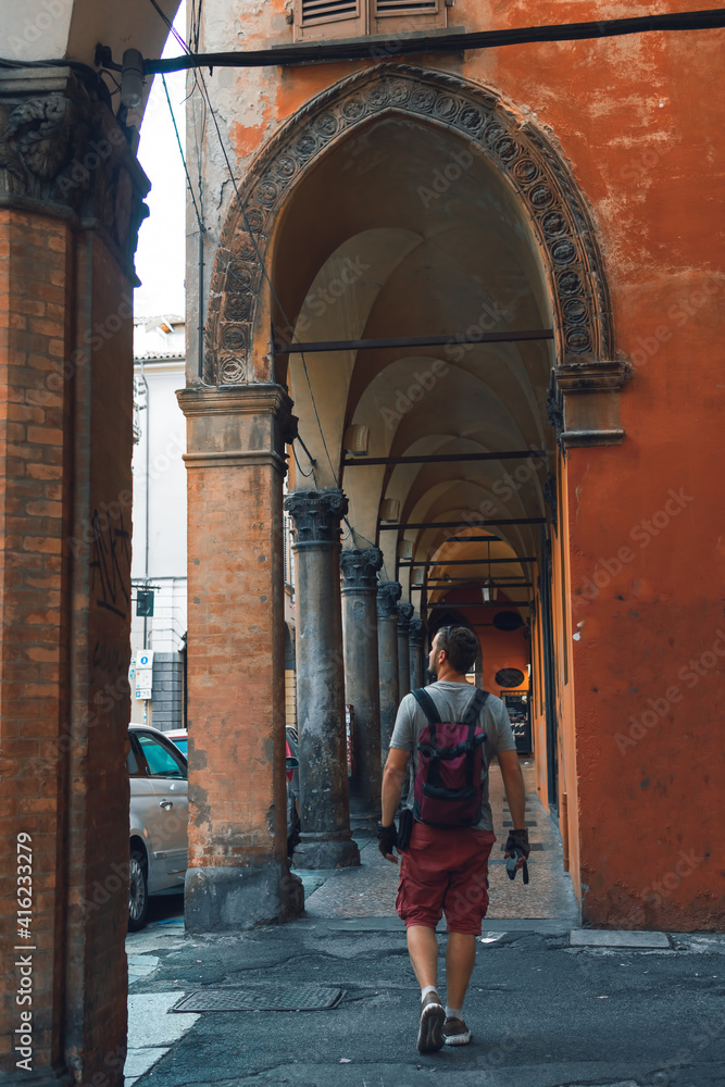 Tourist man with backpack walk on the street in Italy. Summer day. Vertical photo. Bologna