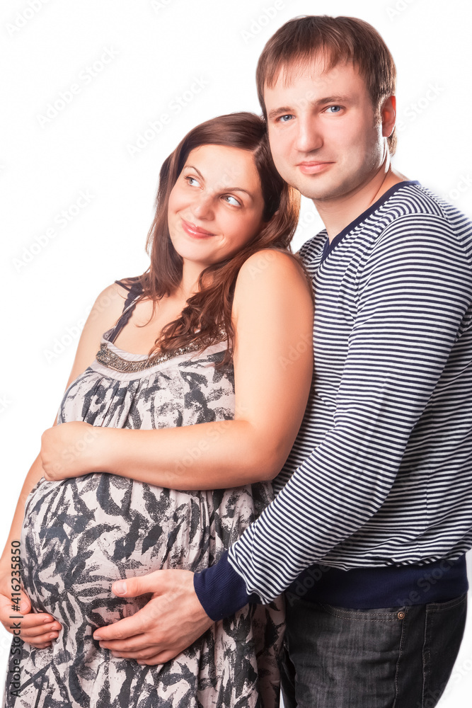 Portrait of Pregnant Caucasian Woman with Husband Standing Together Embraced.Against White. Portrait of Pregnant Caucasian Woman with Husband Standing Together Embraced.Against White.