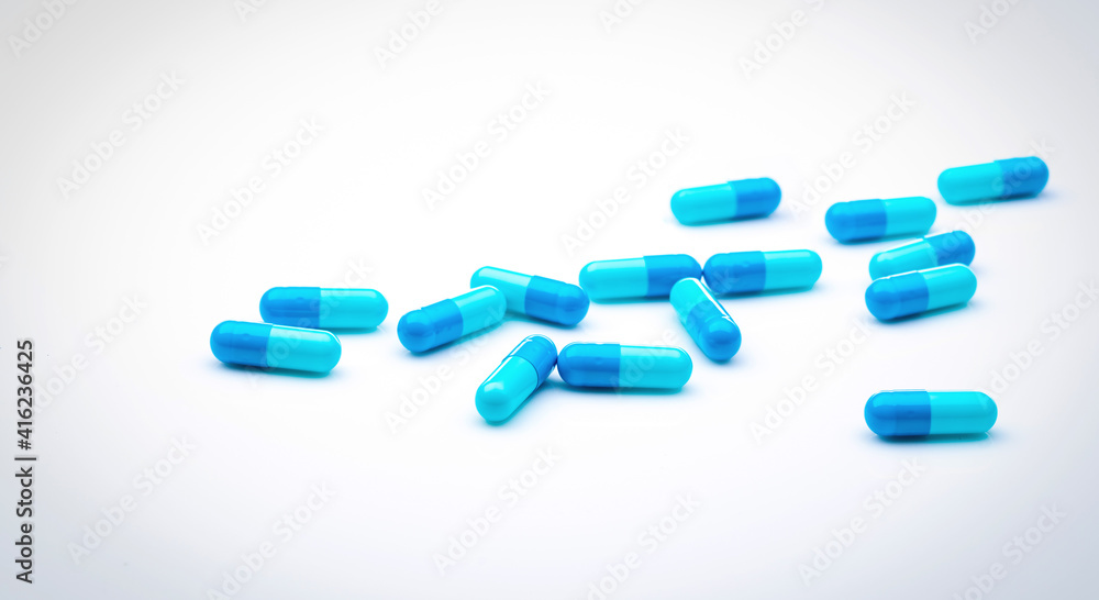 Blue antibiotic capsule pills spread on white background. Antibiotic drug resistance. Pharmaceutical industry. Healthcare and medicine concept. Health budget concept. Capsule manufacturing industry.