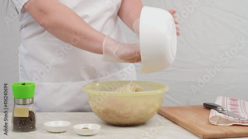 Female hands in gloves add chopped onions to the minced meat. Traditional minced meat for cutlets.
