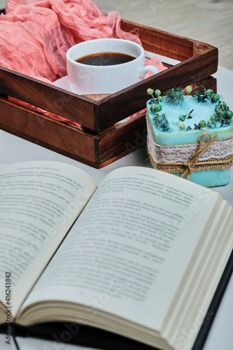 Book with blue candle and basket of cup of coffee