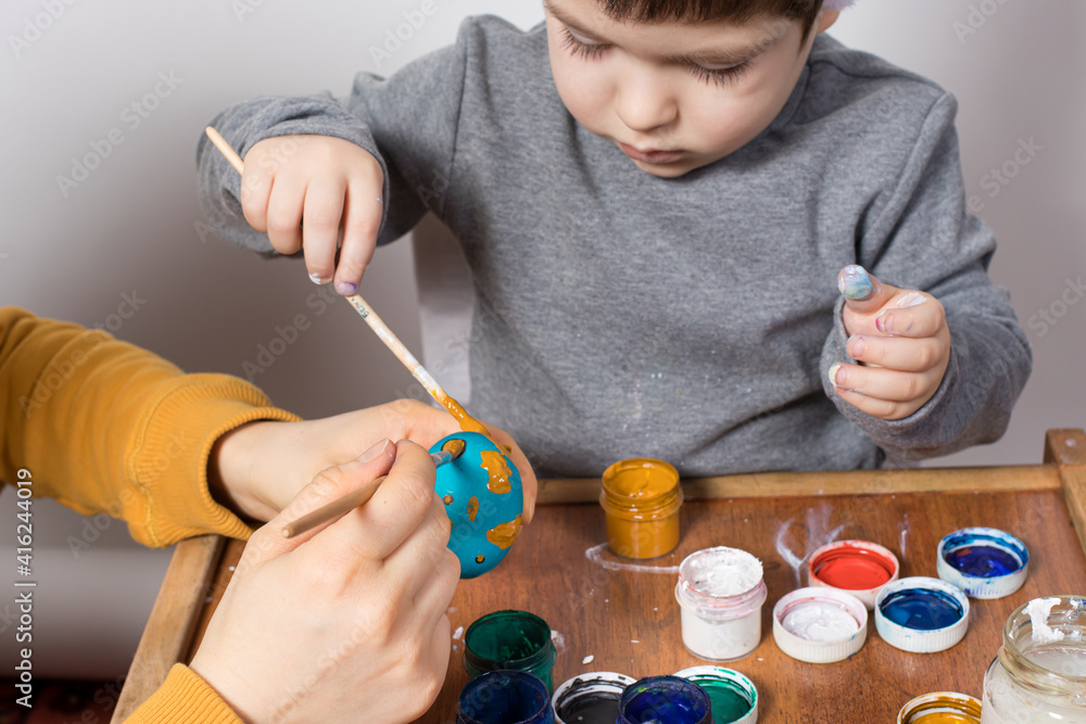 Mother and son paint chicken eggs together for the Easter holiday. Preparing for Easter. Family traditions Mother and son paint chicken eggs together for the Easter holiday. Preparing for Easter. Family traditions