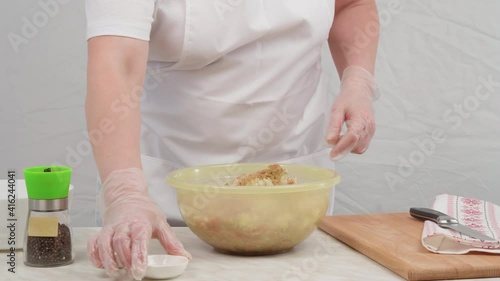 Female hands in gloves add spices, salt and pepper to the minced pork. Traditional minced meat for cutlets.