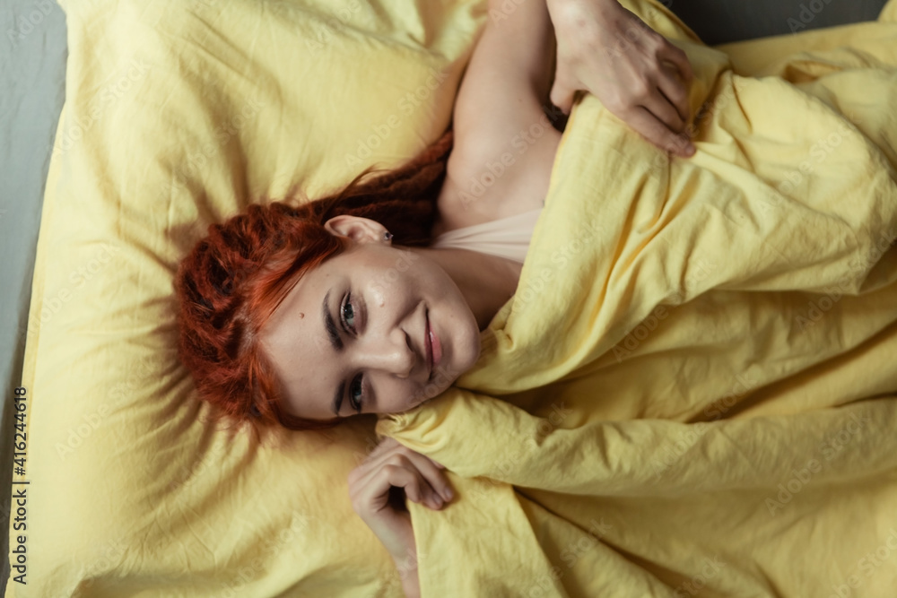 Very pretty redhead girl with dreads on bed in bedroom in the morning. A feminine, gentle girl. Healthcare and Sleep Concept. Very pretty redhead girl with dreads on bed in bedroom in the morning. A feminine, gentle girl. Healthcare and Sleep Concept.