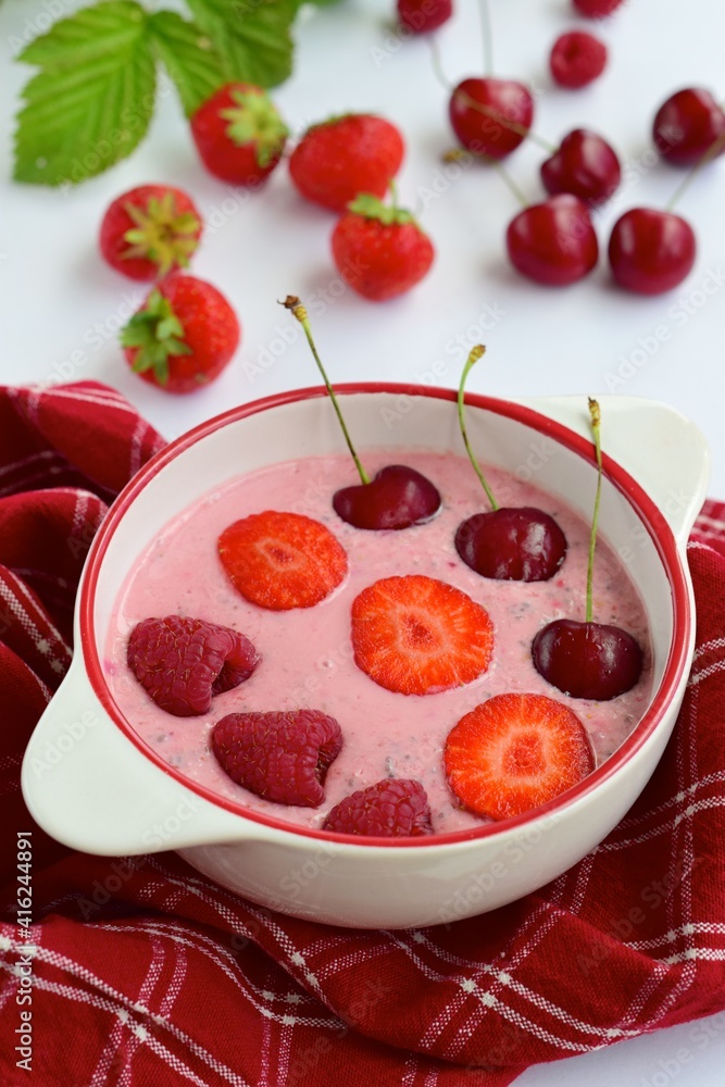 Breakfast berry smoothie bowl topped with raspberry, strawberry and cherry on white background Breakfast berry smoothie bowl topped with raspberry, strawberry and cherry on white background