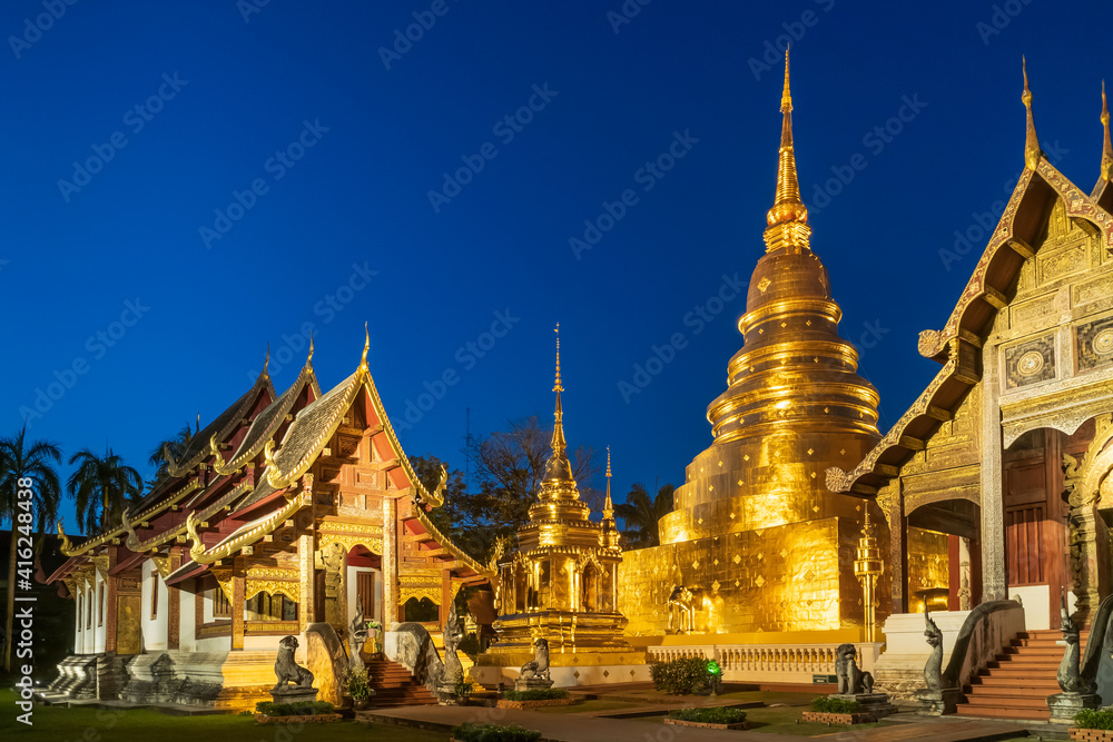 Fototapeta premium Chapel and golden pagoda at Wat Phra Singh Woramahawihan in Chiang Mai at twilight or night with stars in sky