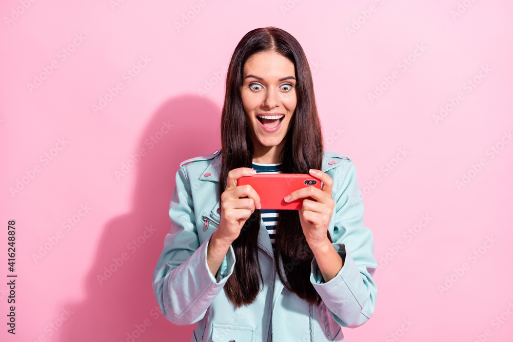 Photo of excited crazy young lady hold phone play video game funky isolated on pink color background Photo of excited crazy young lady hold phone play video game funky isolated on pink color background