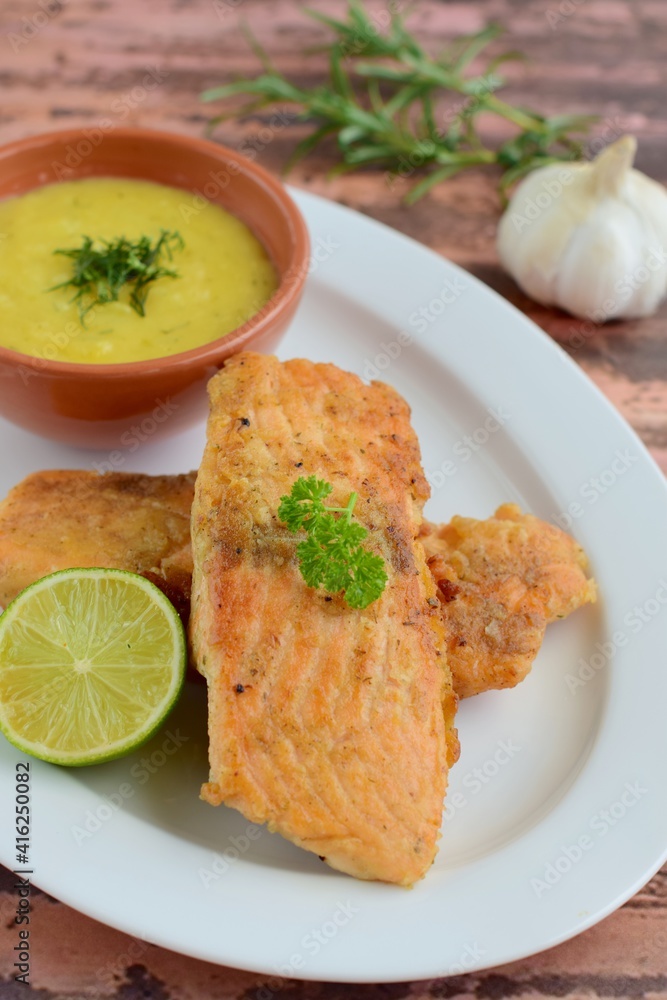 Fried salmon with potato puree garnish with lime and parsley