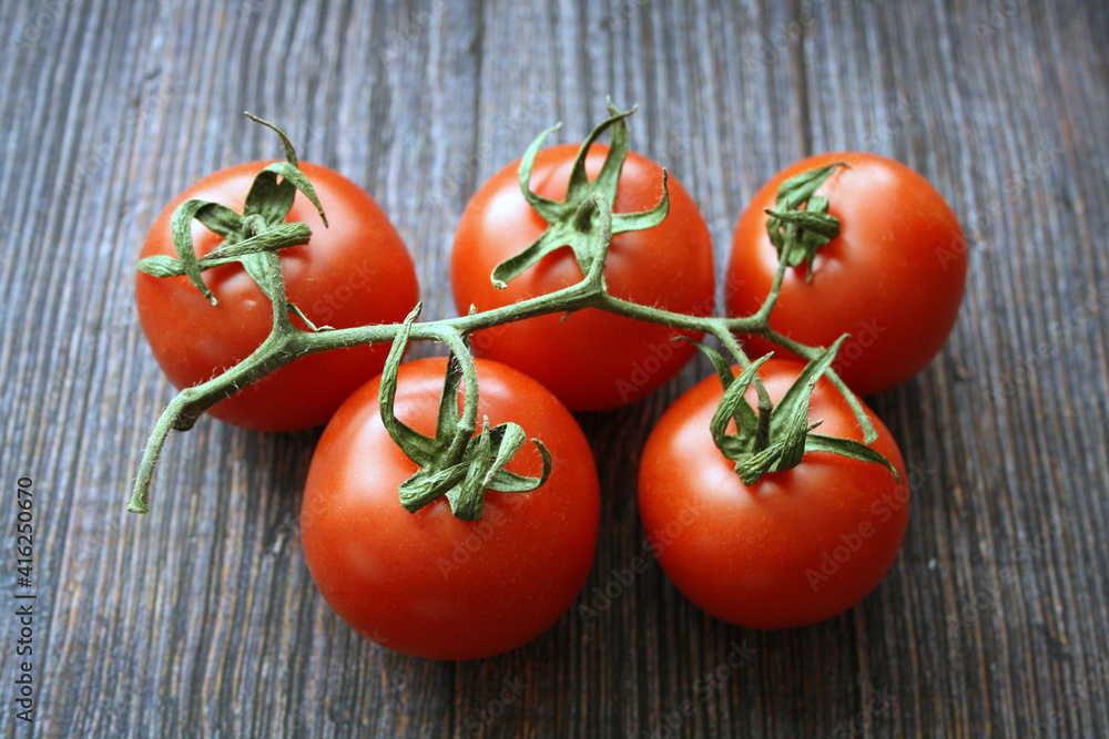 Red tomatoes on a branch on a wooden background. Red tomatoes on a branch on a wooden background.