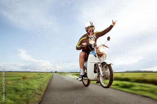 Funny biker doing a wheelie with his moped photo