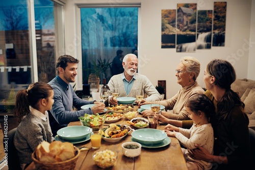 Happy multi-generation family talking during lunch in dining room.