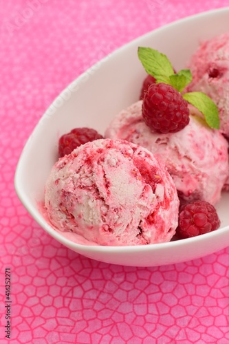 Scoops of raspberry ice cream in a bowl garnish with mint leaves. Summer dessert