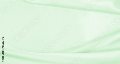 Smooth elegant green silk or satin luxury cloth texture as abstract background. Luxurious background design