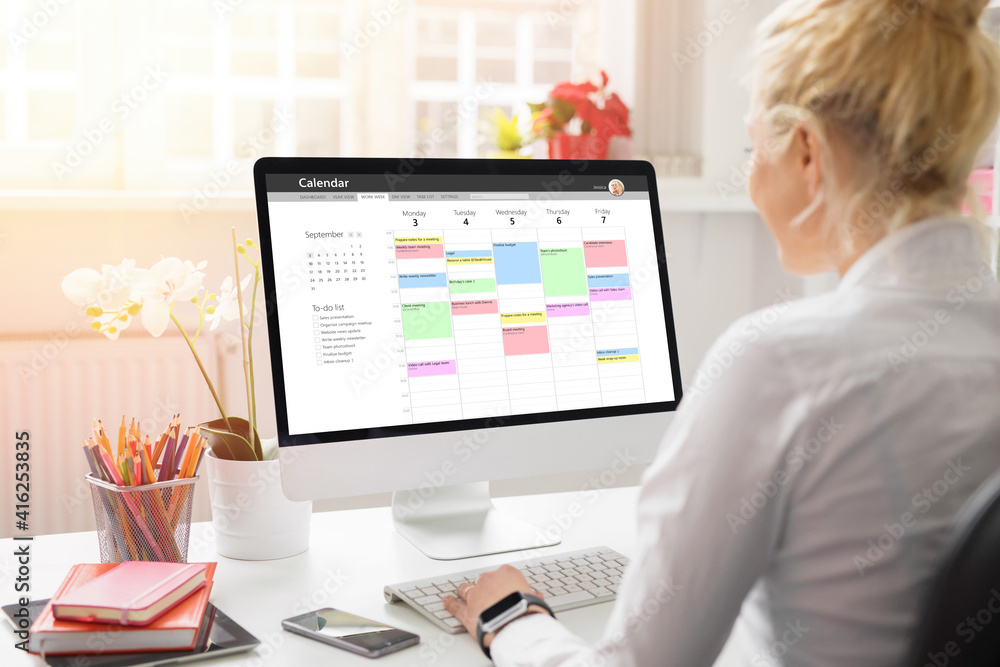 Woman using calendar on computer to organize her schedule at work