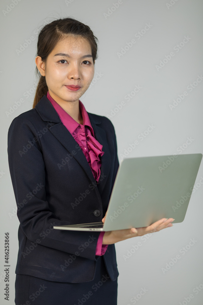 Cute and handsome Asian businesswoman executive look in formal suit standing and holding laptop notebook computer Cute and handsome Asian businesswoman executive look in formal suit standing and holding laptop notebook computer