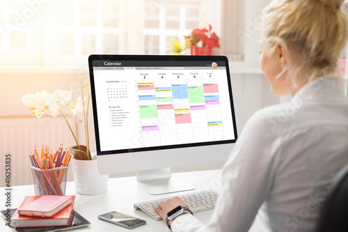 Woman using calendar on computer to organize her schedule at work