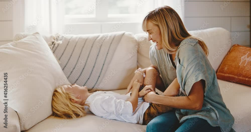 Mother and cute young kid playing on the couch, laughing and tickling, family lifestyle at home Mother and cute young kid playing on the couch, laughing and tickling, family lifestyle at home