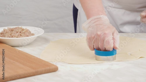 The cook cuts dough circles with a mold on the table for ravioli, tortellini.