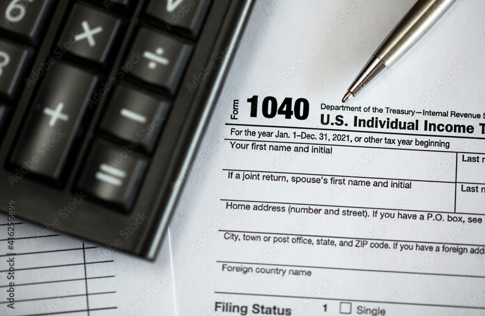 Tax time concepts. 1040 tax form on wooden table with pen and calculator Tax time concepts. 1040 tax form on wooden table with pen and calculator