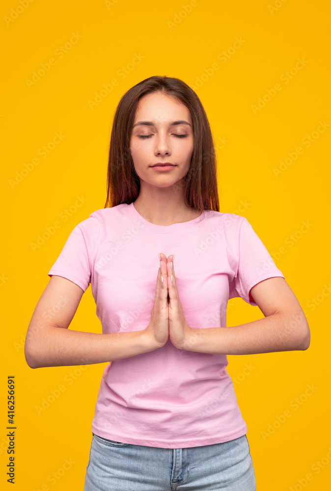 Young woman meditating with closed eyes and clasped hands Young woman meditating with closed eyes and clasped hands