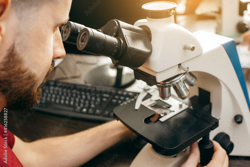 A doctor sits in a laboratory and makes a study under a microscope A doctor sits in a laboratory and makes a study under a microscope