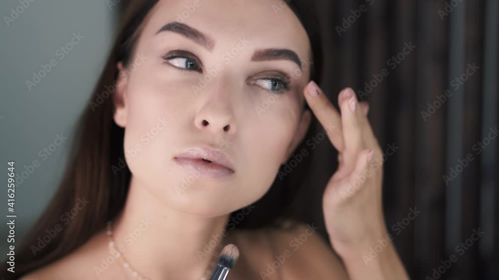 Side view of cute beautiful young woman makeup artist applying eye shadow Side view of cute beautiful young woman makeup artist applying eye shadow