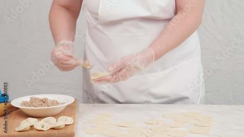 A woman makes traditional dumplings with minced pork at home. Delicious national food.