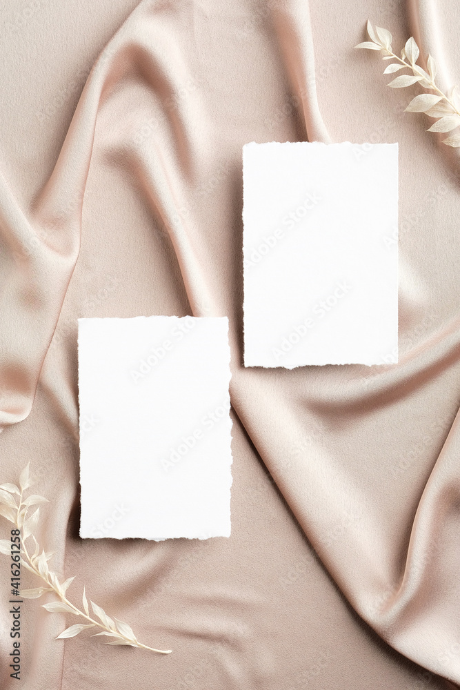 Flat lay wedding invitations mockups and flowers on beige silk. Top view with copy space. Elegant wedding stationery set. Flat lay wedding invitations mockups and flowers on beige silk. Top view with copy space. Elegant wedding stationery set.