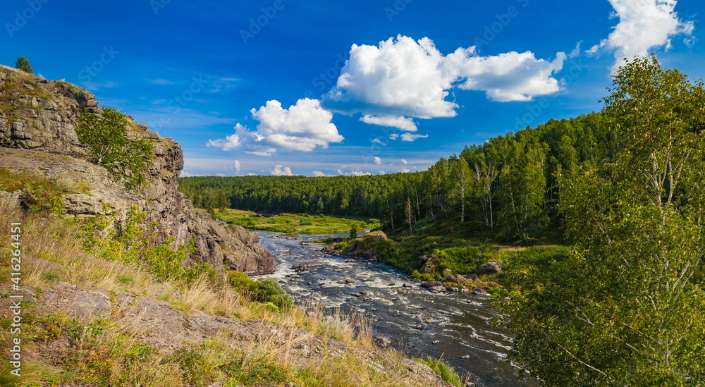 Fast river with rocky banks, overgrown with trees in summer Fast river with rocky banks, overgrown with trees in summer