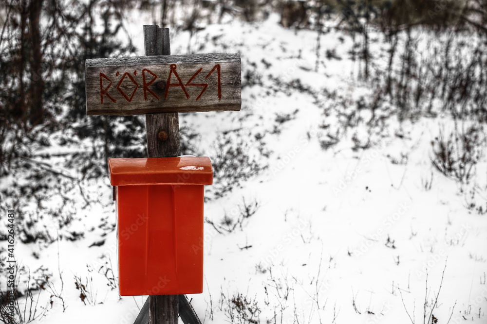 Archaic street sign with a red mailbox in snow