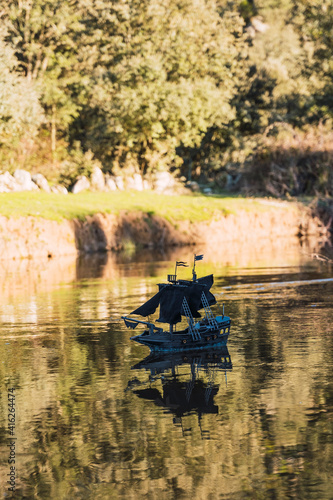 A black toy pirate ship sailing on the river 