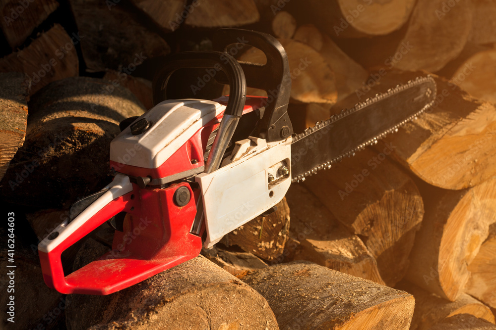 Chainsaw against the background of sawn trees. Woodworking industry. Logs of trees. 